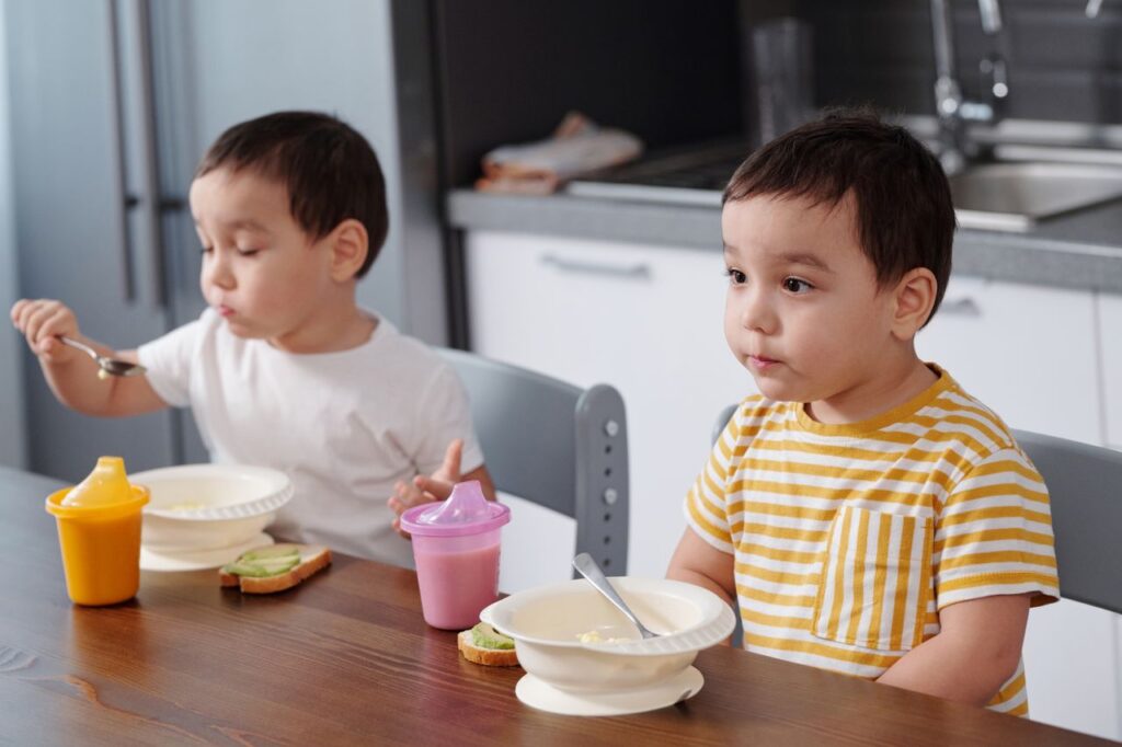 Two young boys enjoy breakfast together in a modern kitchen setting.